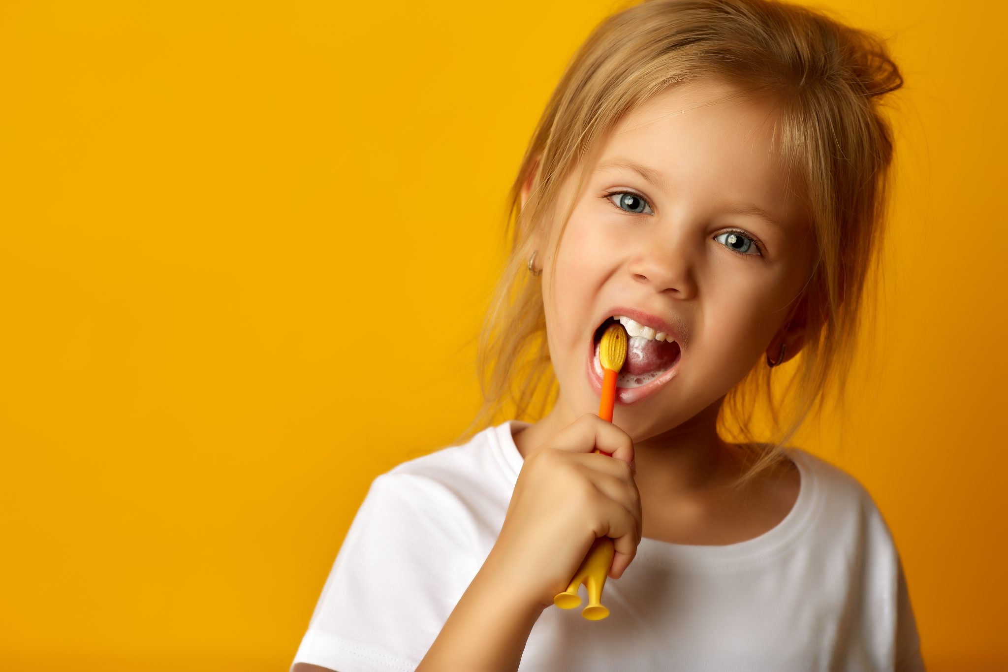 Charming Little Girl In White T Shirt Cleaning Teeth With Colorful Kids Toothbrush Looking At Camera
