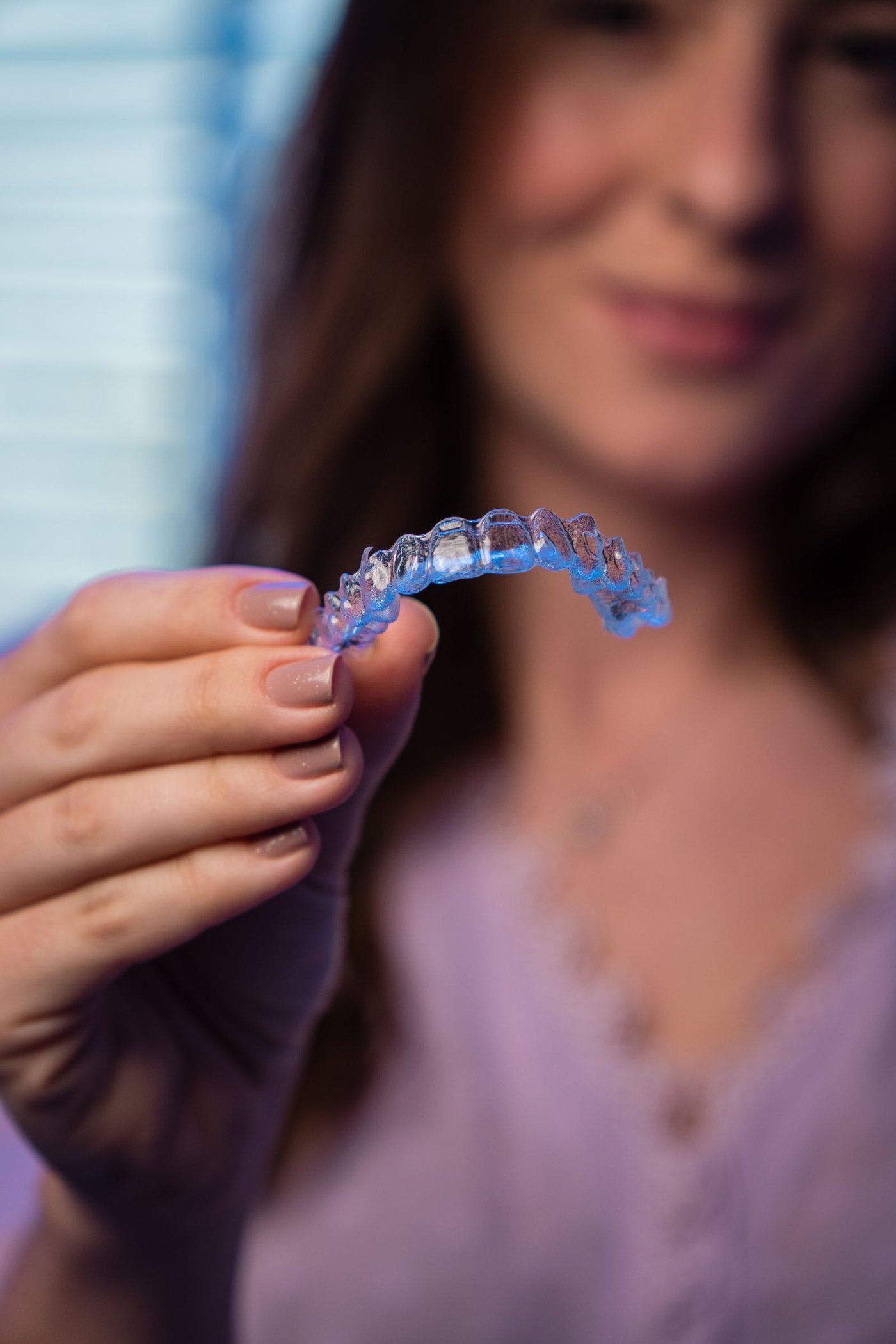 Close up of a clear aligner tray held between finger and thumb